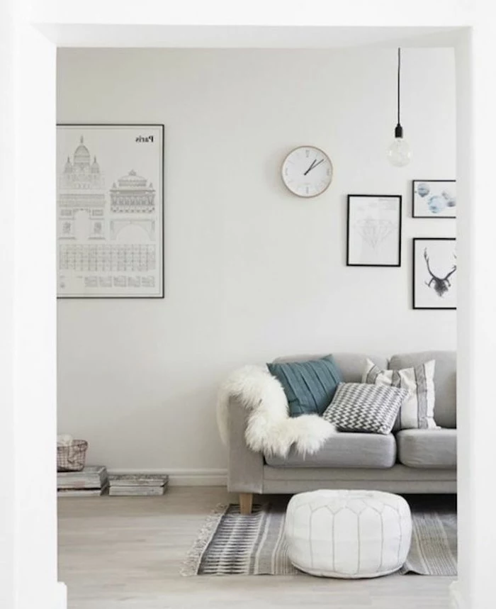 white ottoman, grey sofa, light gray walls, framed hanging art, blue throw pillow, yellow furry blanket