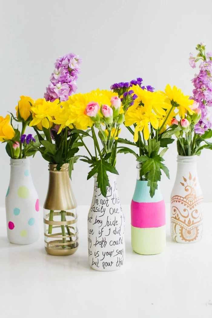 glass bottles, painted in different colours, kitchen table centerpieces, white background, flower bouquets