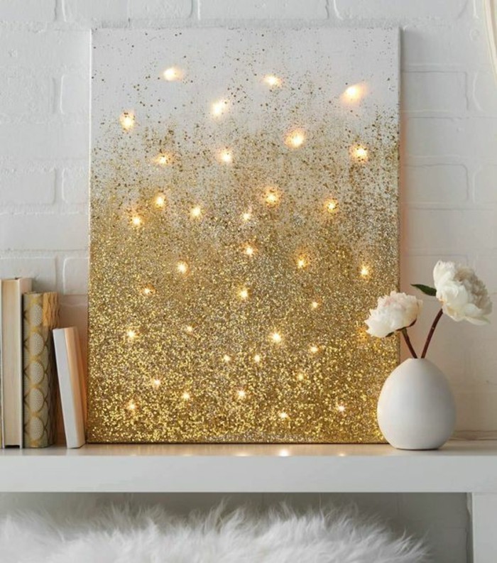 wall art ideas for living room, white canvas, covered in gold glitter, lights behind it, on a white table