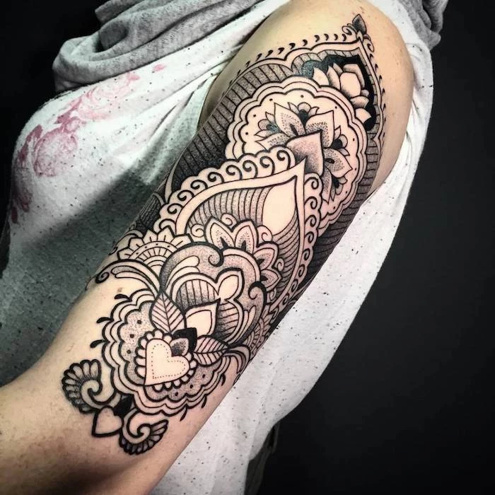 grey top, black background, mandala symbols, shoulder tattoo