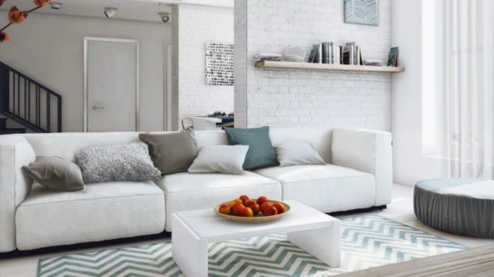 small white coffee table, gray living room walls, white brick wall, white sofa, blue and beige throw pillows