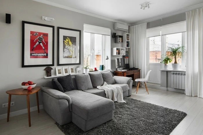 grey corner sofa, framed hanging posters, wooden side table, grey carpet, wooden floor, gray living room walls