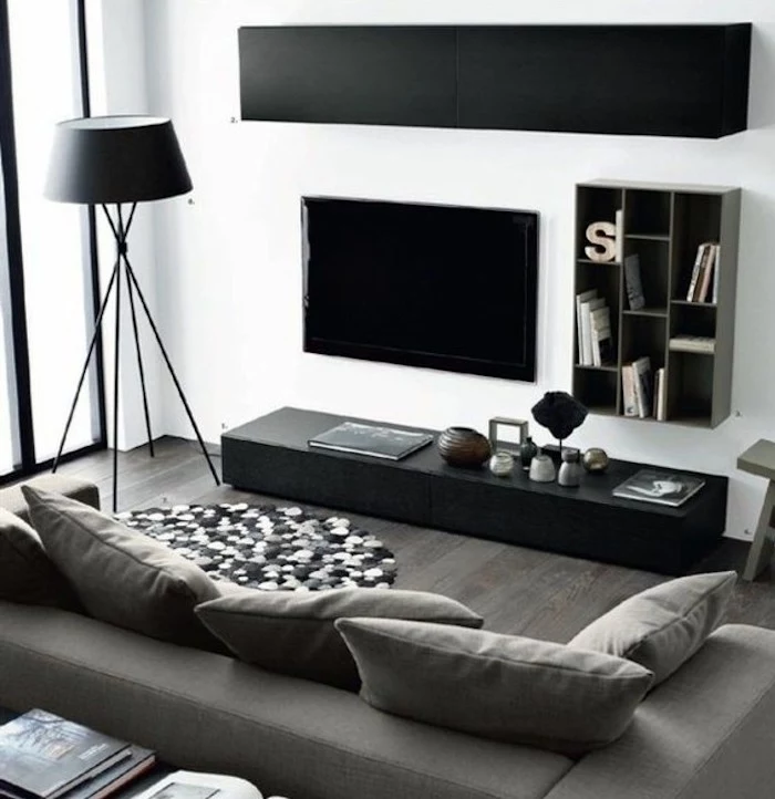 black cabinets, grey sofa, wooden floor, grey living room walls, rug made of pom poms