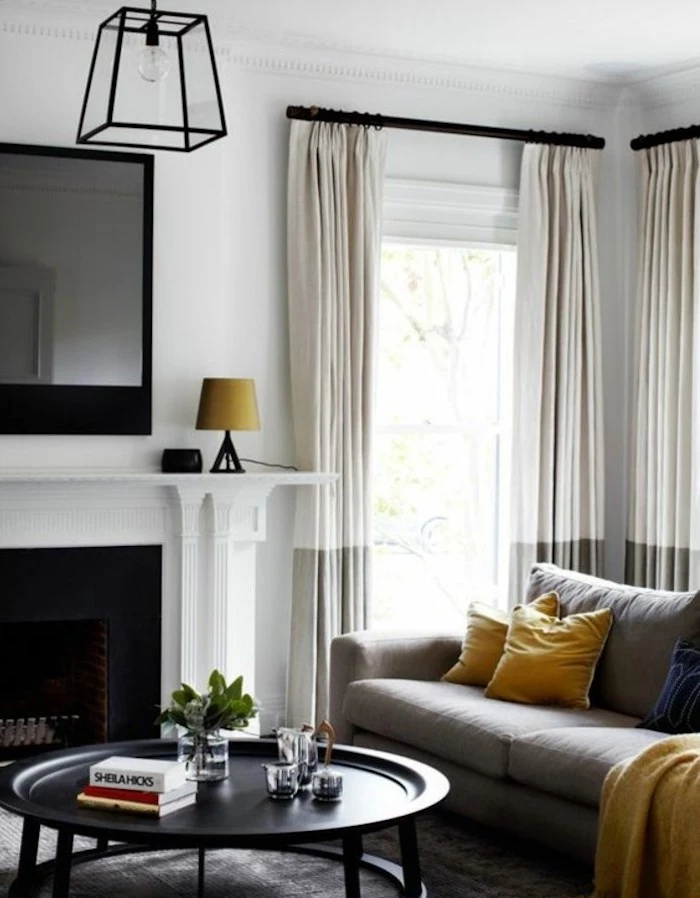 tv above the fireplace, grey living room walls, black metal coffee table, grey sofa, yellow throw pillows