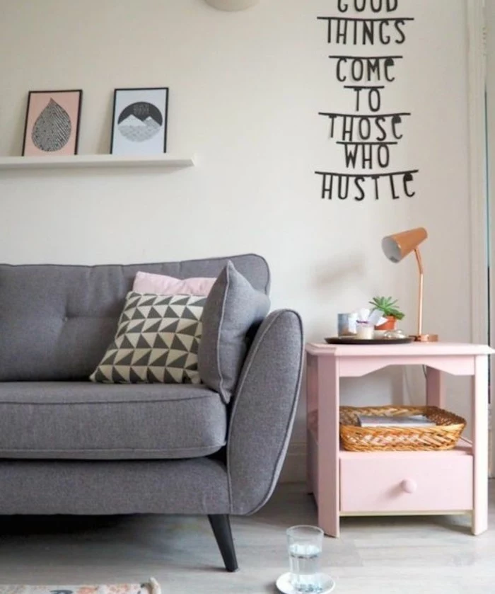 grey sofa, printed throw pillows, pink side table, grey living room walls, hanging shelf, framed art
