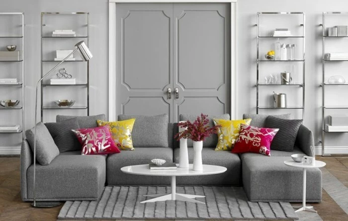 grey living room walls, grey corner sofa, pink and yellow, throw pillows, grey carpet, white coffee table