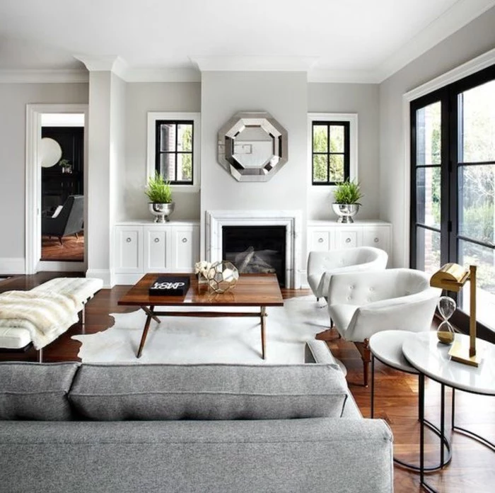 white armchairs, mirror above the fireplace, accent colors for gray, grey sofa, wooden coffee table