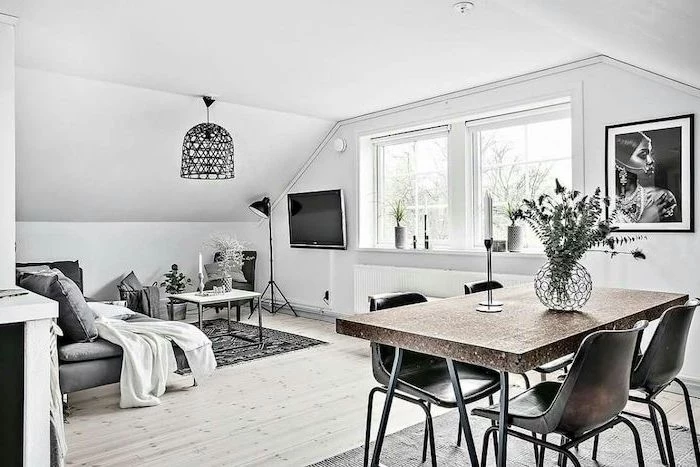 living room setup, grey sofa, metal black chairs, wooden floor, grey and black rug, small metal coffee table