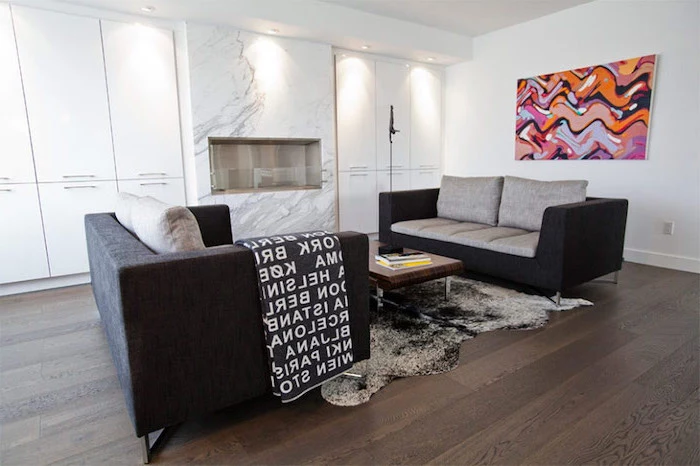 black and grey sofas, wooden floor, marble accent wall, living room setup, white cabinets