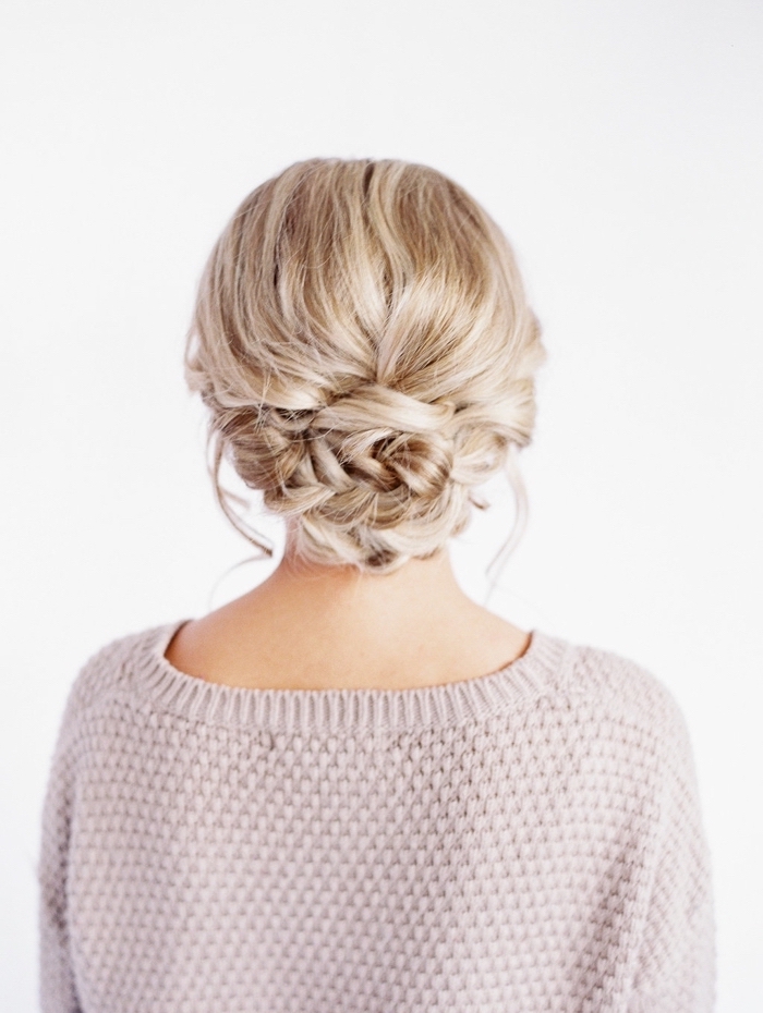 woman wearing a grey sweater, with a low updo, braid hairstyles for girls, blonde hair, in a braided bun
