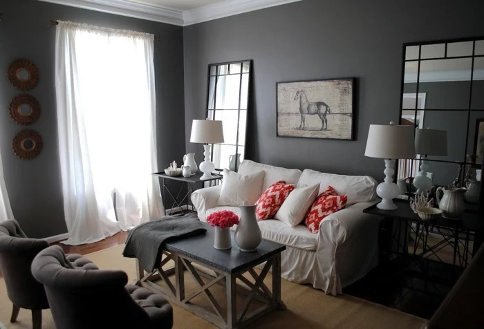 white sofa, colors that go with gray walls, red printed throw pillows, large mirrors, grey armchairs