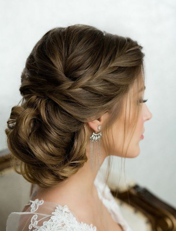 brown hair, in a low updo, braided bun, updo hairstyles for prom, white lace dress, hanging earrings
