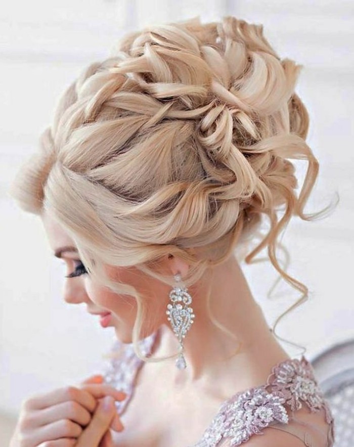 easy hairstyles for girls, blonde hair, in a high messy updo, crystal hanging earrings, purple lace dress