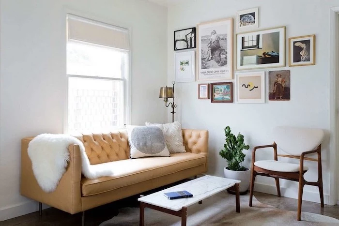 small room decor, brown leather couch, wood and marble, coffee table, hanging art, white walls