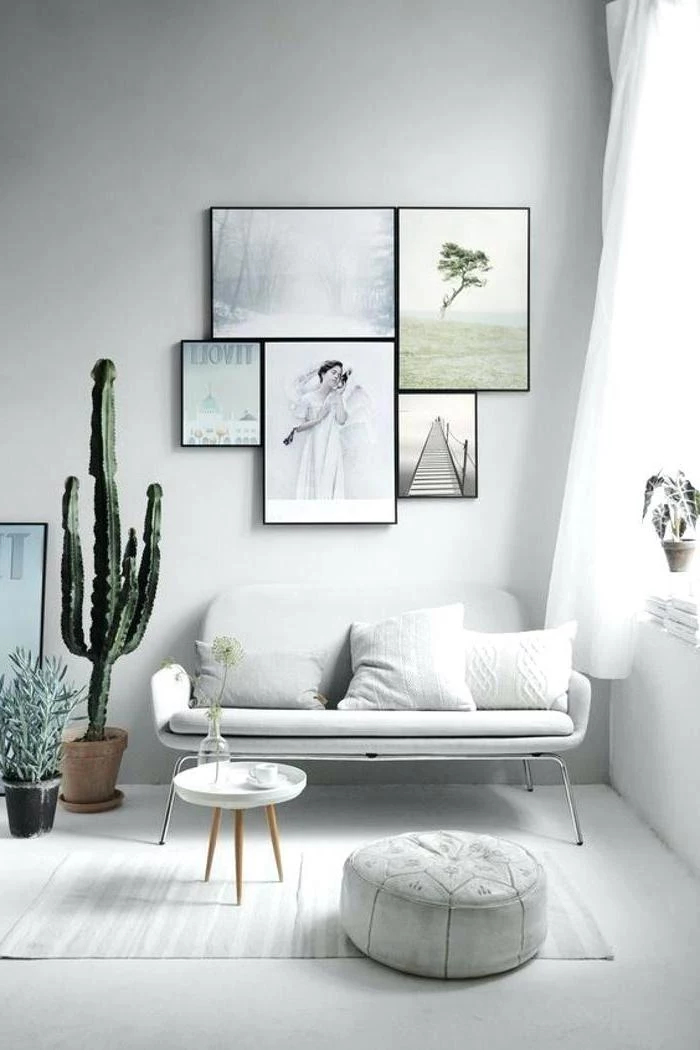 living room arrangements, white sofa, hanging art, white ottoman and rug, potted plants, small coffee table