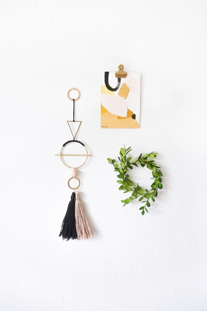 greenery wreath, beige and black macrame tassel, abstract drawing, hanging on a white wall, diy wall art