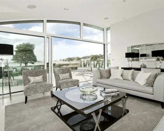 large tall windows, glass coffee table, grey leather sofa, grey armchairs, gray bedroom walls