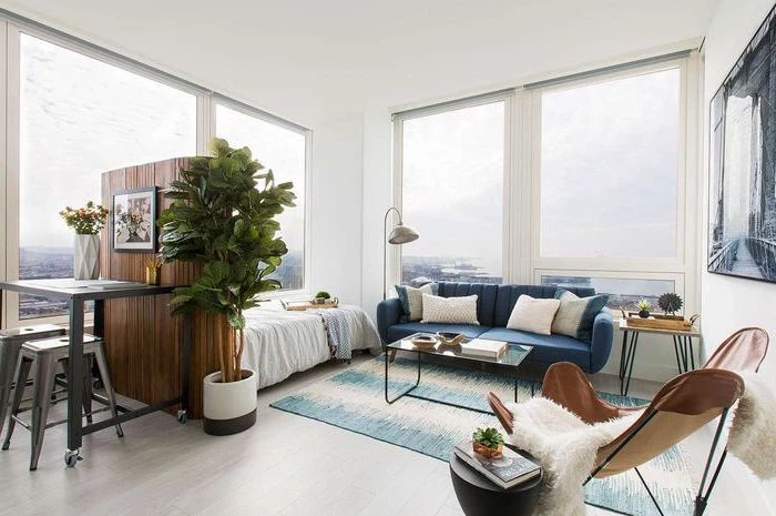 blue sofa, large windows, wooden room divider, wooden floor, living room arrangements, small metal coffee table