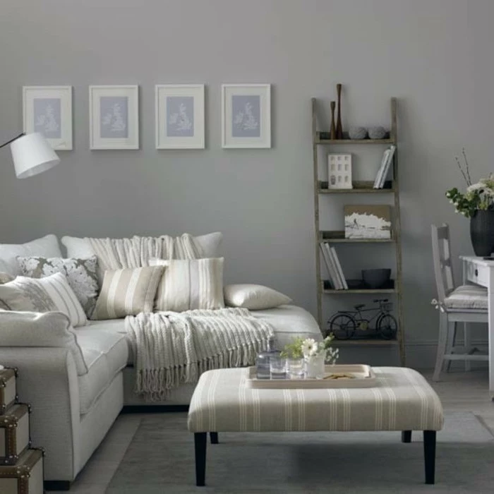 grey ottoman, white corner sofa, vintage bookshelf, gray bedroom walls, beige printed throw pillows