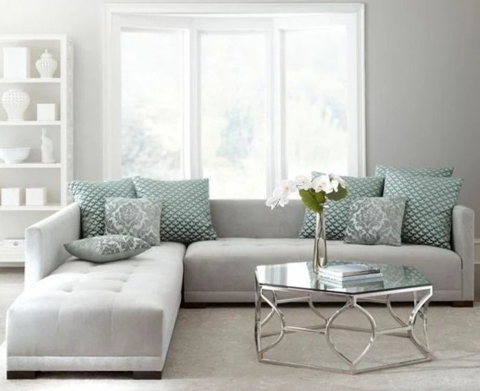 light grey corner sofa, turquoise printed throw pillows, gray bedroom walls, glass coffee table