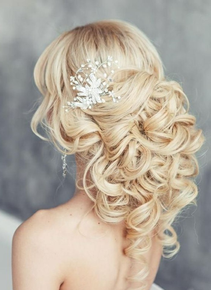 blonde wavy hair, floral hair accessory, prom hairstyles down, in a low messy updo, grey background