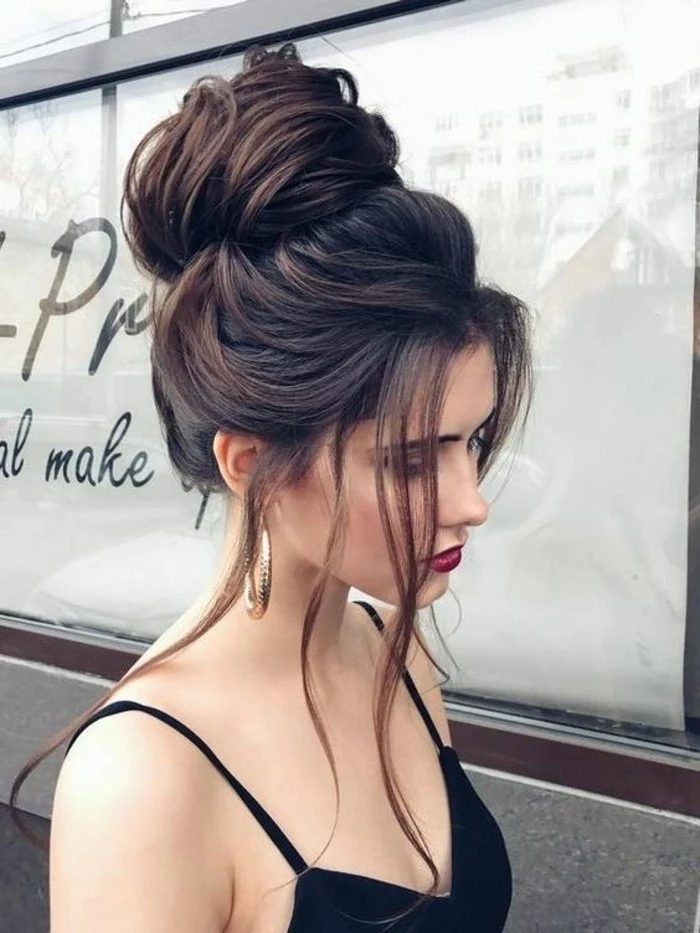 black hair, in a high messy updo, short prom hairstyles, woman wearing a red lipstick, black top
