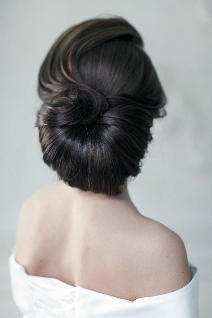 black hair, in a low updo, wedding hairstyles updo, woman wearing a white top