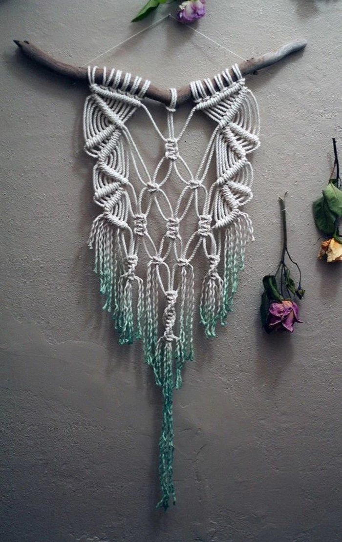 white macrame, hanging off a tree branch, on a grey wall, big wall decor, dried flowers around