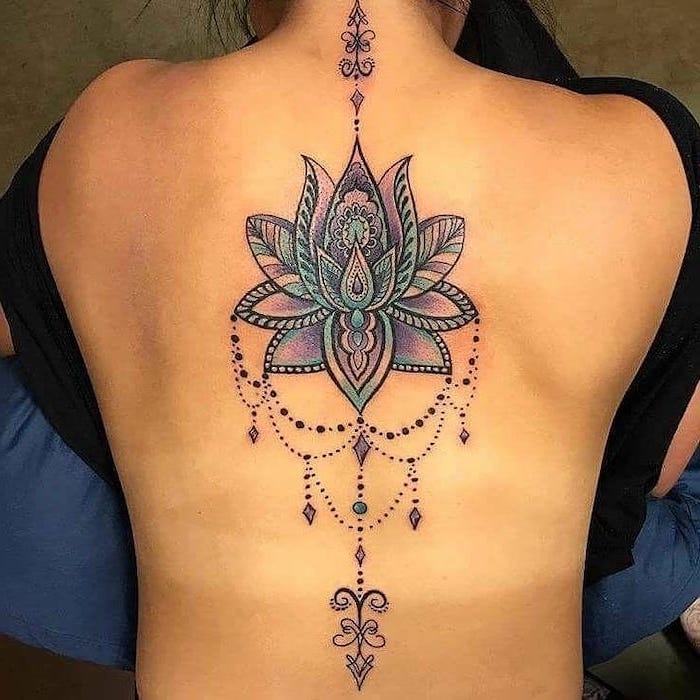 mandala tattoo meaning, colourful lotus, back tattoo, black top, blue cushions