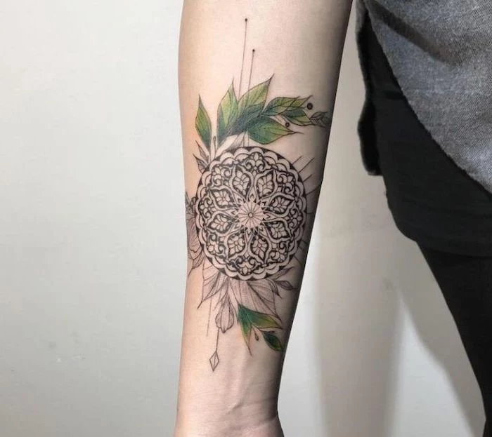grey sweater, black pants, white background, what does mandala mean, forearm tattoo