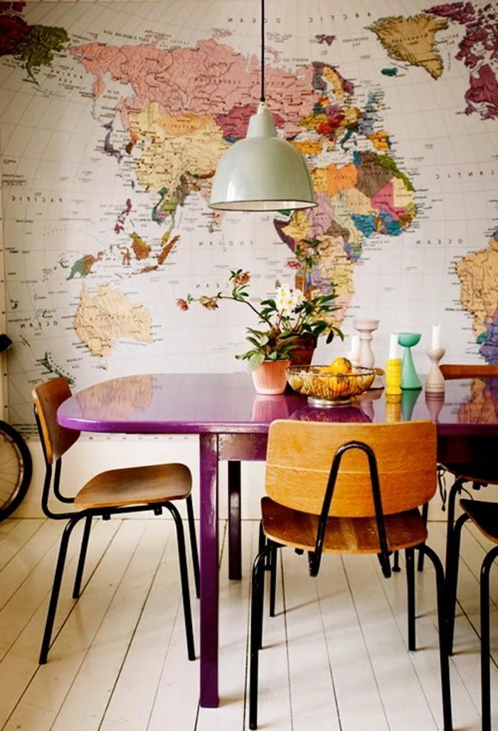 map of the world wallpaper, purple wooden table, center table decor, wooden chairs, potted flowers, candle holders