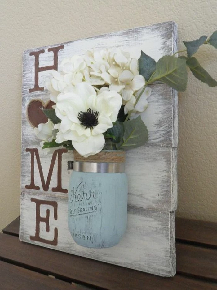 blue mason jar, bouquet of faux flowers inside, stuck to a wooden block, big wall decor, home sign