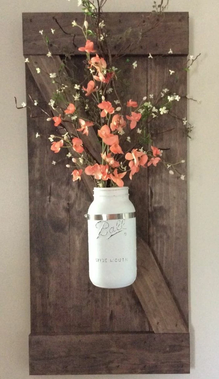 white mason jar, stuck to a wooden block, cute wall decor, orange flower bouquet inside