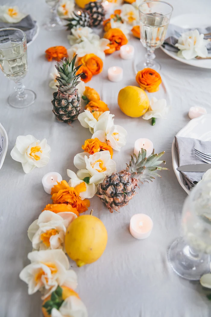 pineapples and lemons, white and orange flowers, table runner, candle decoration, candles scattered