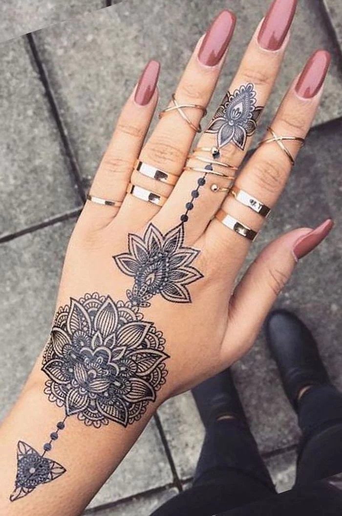 pink nail polish, silver rings, hand tattoo, mandala tattoo meaning, paved street