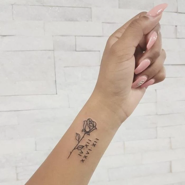 long pink nails, rose and numbers, roman numerals translation, wrist tattoo, white tiled wall