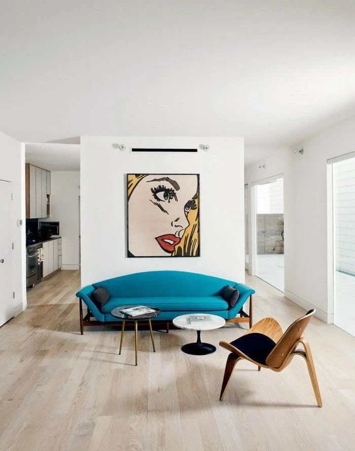 how to decorate a living room, blue sofa, hanging pop art, wooden floor, small metal coffee tables, white walls