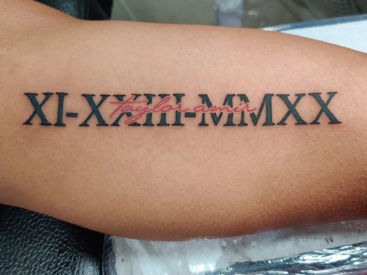 red and black bicep tattoo of roman numerals
