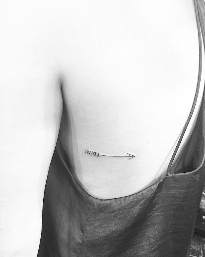 arrow rib cage tattoo, black and white photo, birthday tattoos in roman numerals, black top, roses with roman numerals