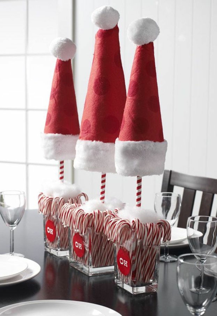 small square glass vases, full of candy canes, simple centerpieces, christmas hats, wooden table and chairs