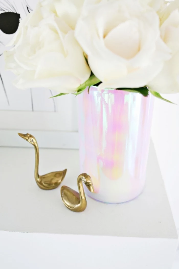 metal swan figurines, monochromatic vase, table setting ideas, bouquet of white roses, framed drawing