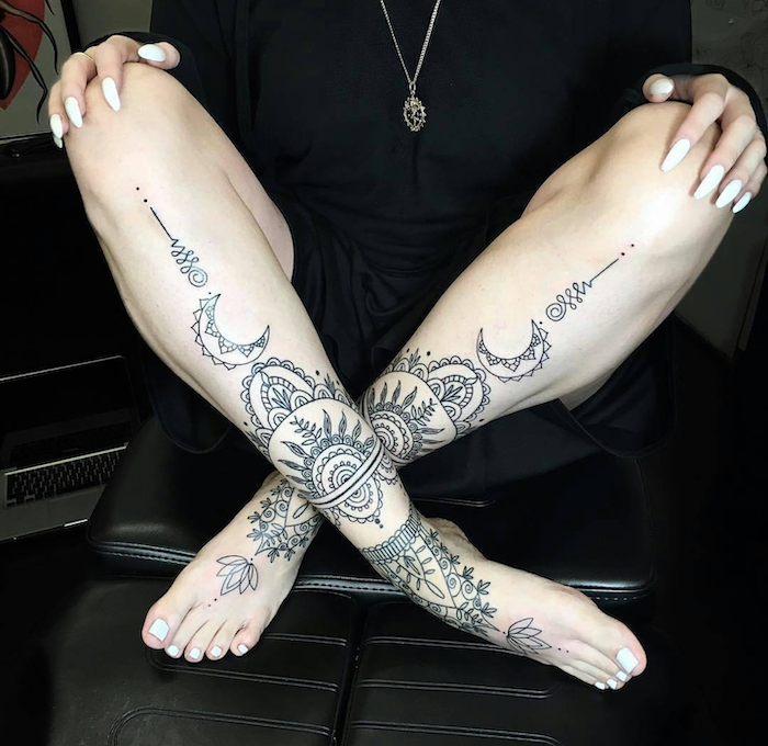 black leather armchair, white nail polish, leg tattoos, mandala wrist tattoo
