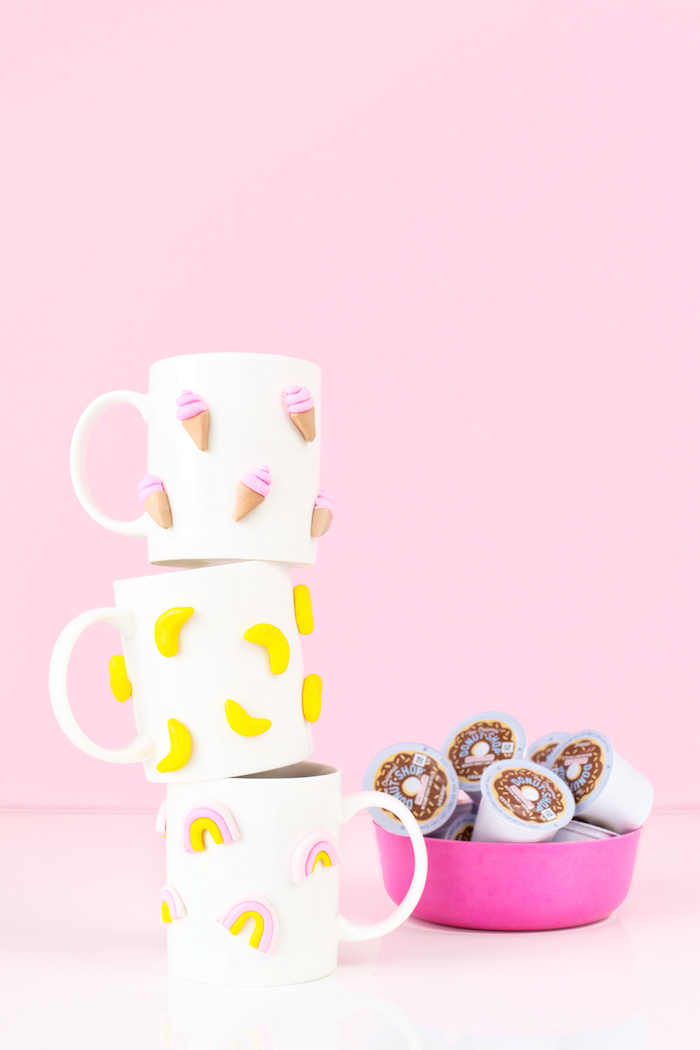 pink background, stack of white coffee mugs, diy gifts for friends, ice cream bananas and rainbow figurines