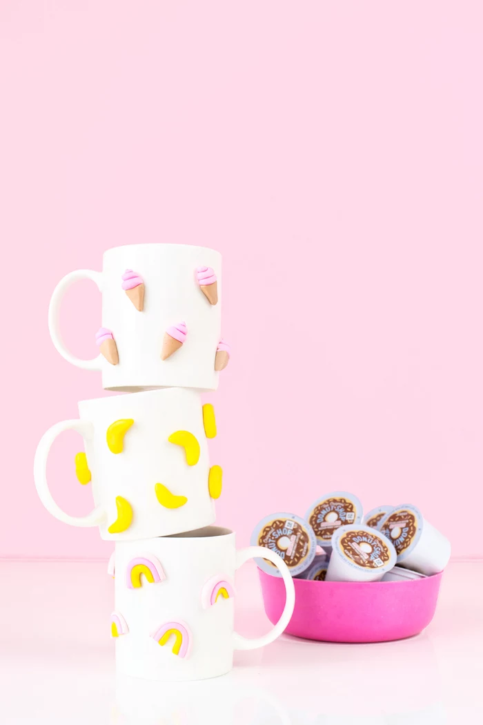 pink background, stack of white coffee mugs, diy gifts for friends, ice cream bananas and rainbow figurines