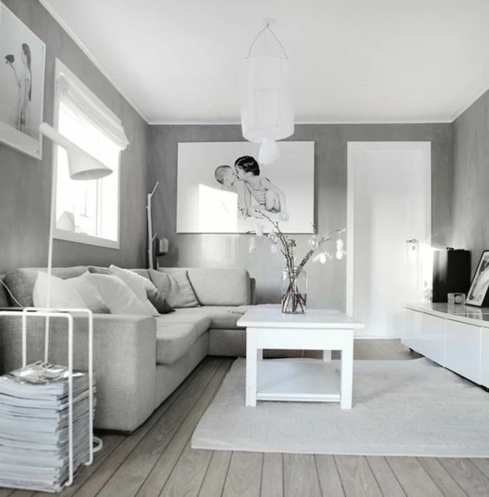 grey walls, white wooden coffee table, grey corner sofa, wooden floor, hanging photos, gray color schemes