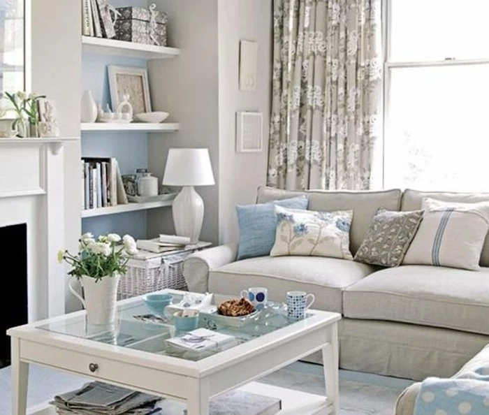 grey sofa, blue printed throw pillows, gray color schemes, glass coffee table, hanging shelves
