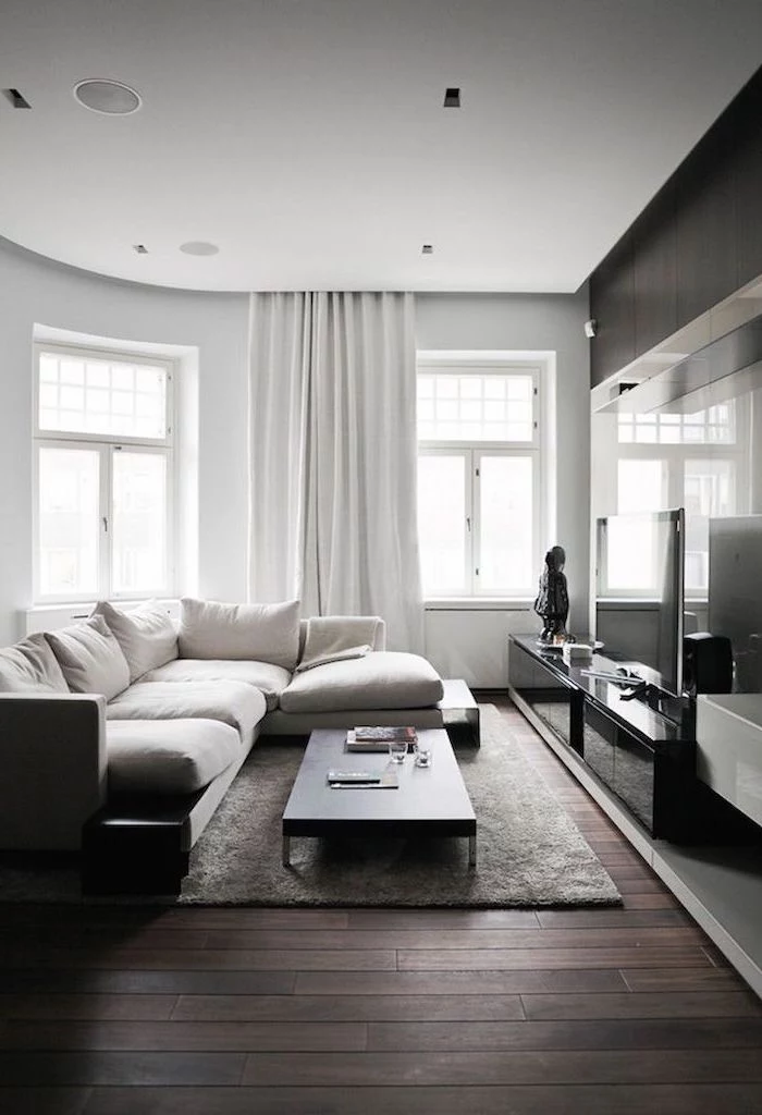 white corner sofa, how to decorate a small living room, small coffee table, dark wooden floor, white curtains