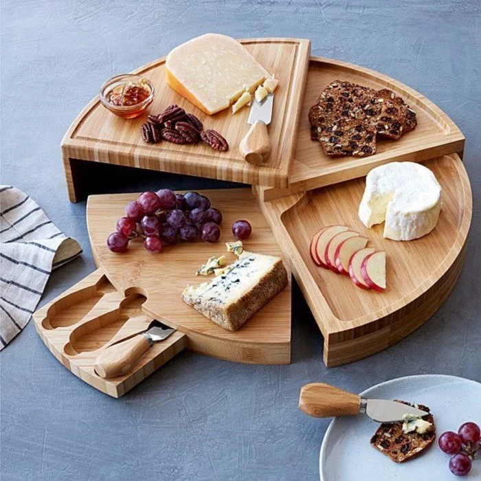 wooden rotating cheese board, what is a good housewarming gift, grapes and cheese, slices of apple, nuts and honey