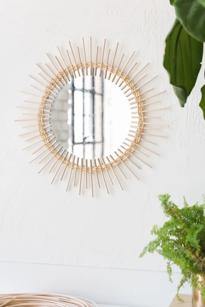 round mirror, frame made out of wooden sticks, large wall decor, hanging on a white wall