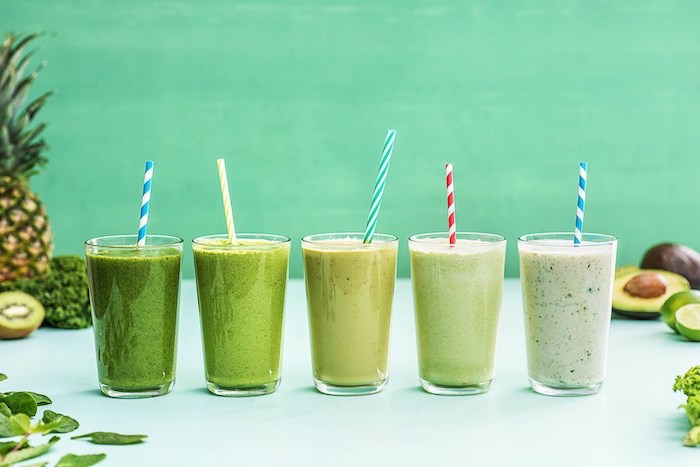 how to make a smoothie, glasses filled with smoothies, in different shades of green, fruits scattered around